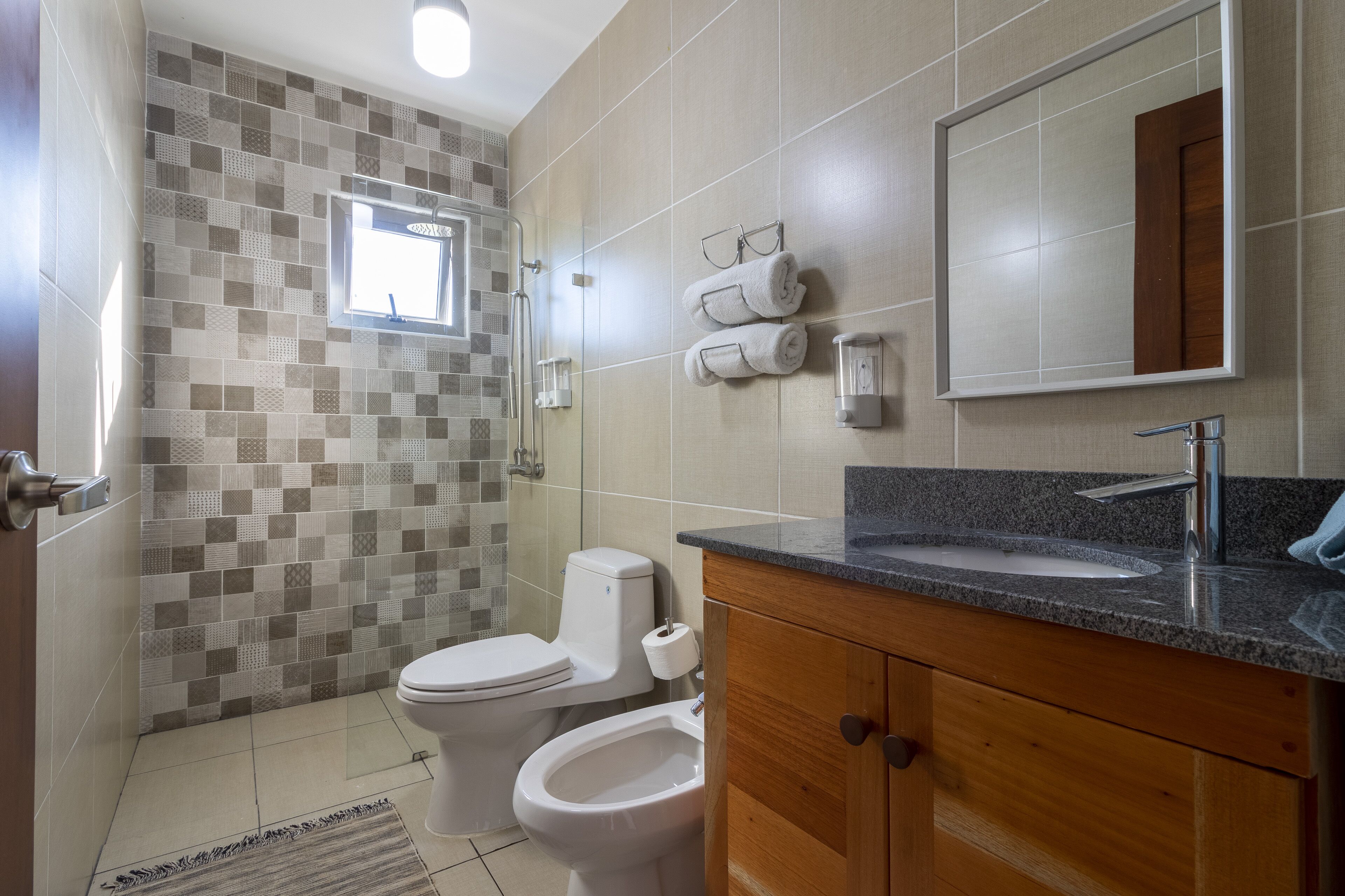 A modern bathroom with a shower, toilet, bidet, and vanity with a sink.