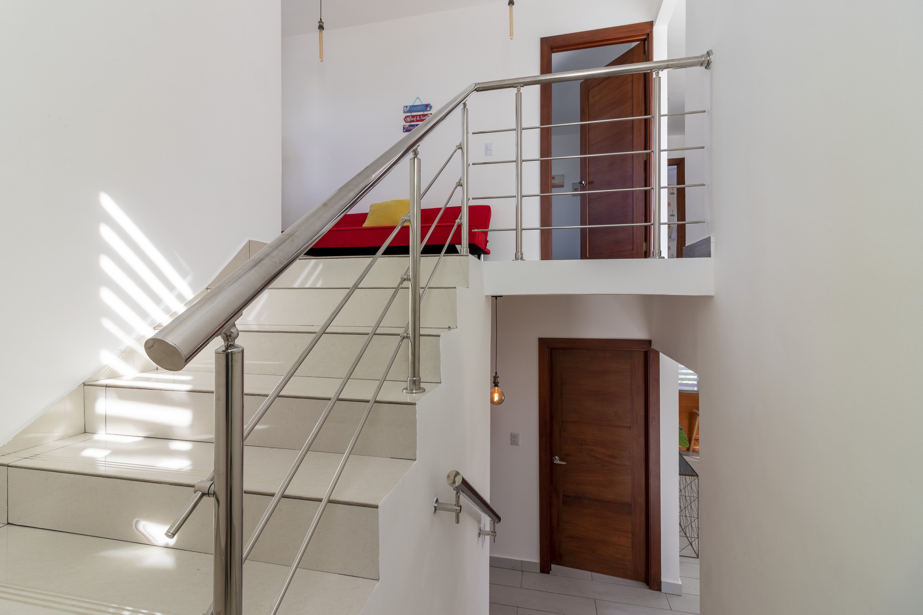 Un interior moderno con una escalera, una puerta de madera y una cama roja.