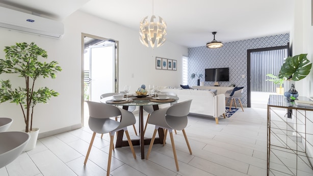 A modern dining area with a round table, grey chairs, and a hanging light fixture. - Modern 4-BR Villa in Gated Community (Punta Cana)