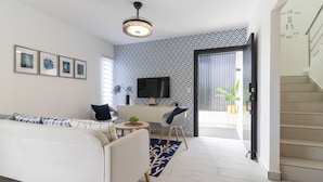 A modern living room with a sofa, a coffee table, a TV, and a patterned wall. - Modern 4-BR Villa in Gated Community (Punta Cana)