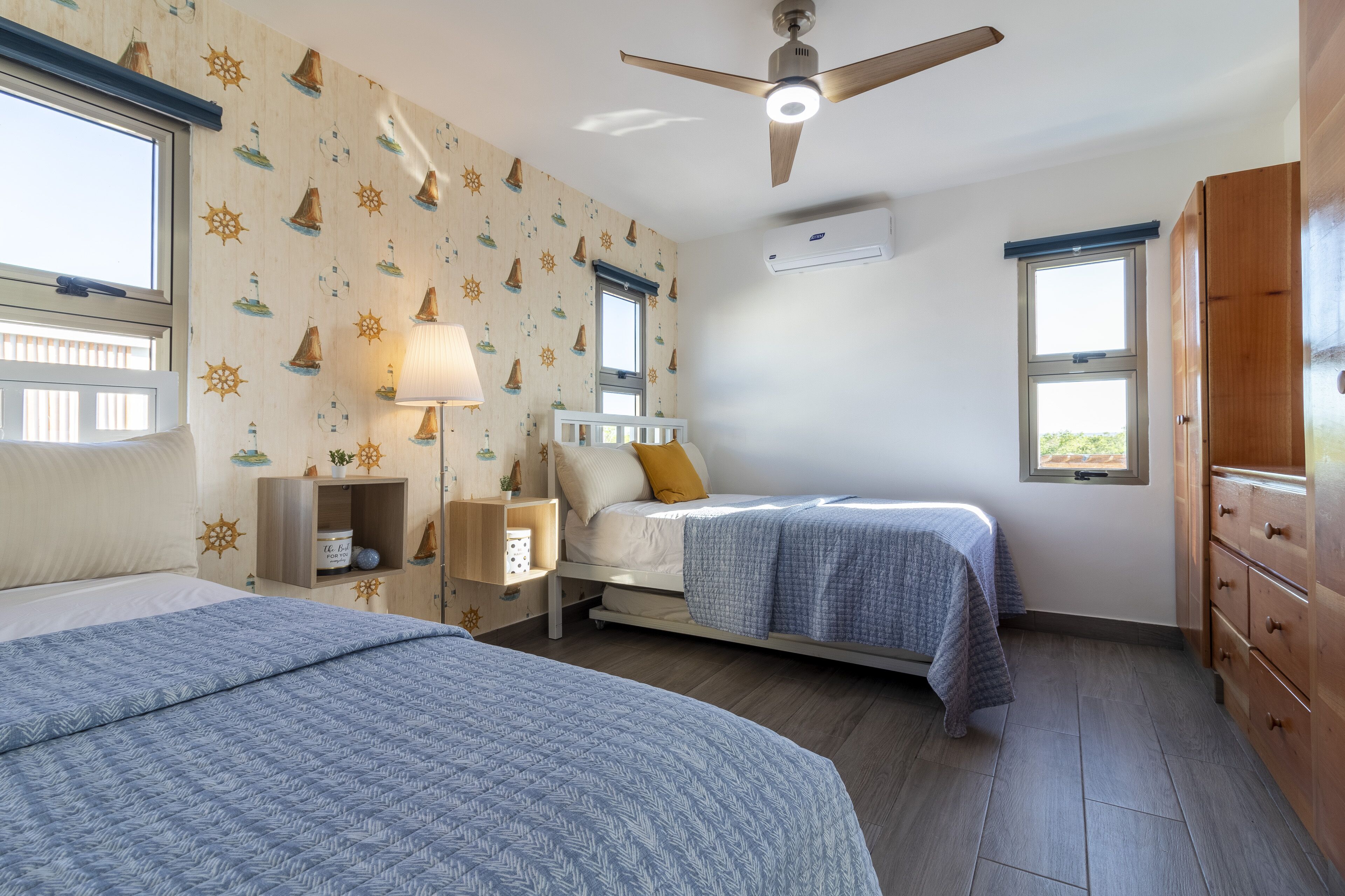 Quarto com duas camas, um ventilador de teto, ar condicionado e janela com vista.