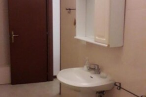 A compact bathroom with a sink and mirror, offering basic amenities for personal hygiene.