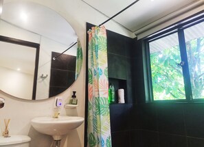 Enjoy a refreshing shower with a view of lush greenery from the bathroom's window.