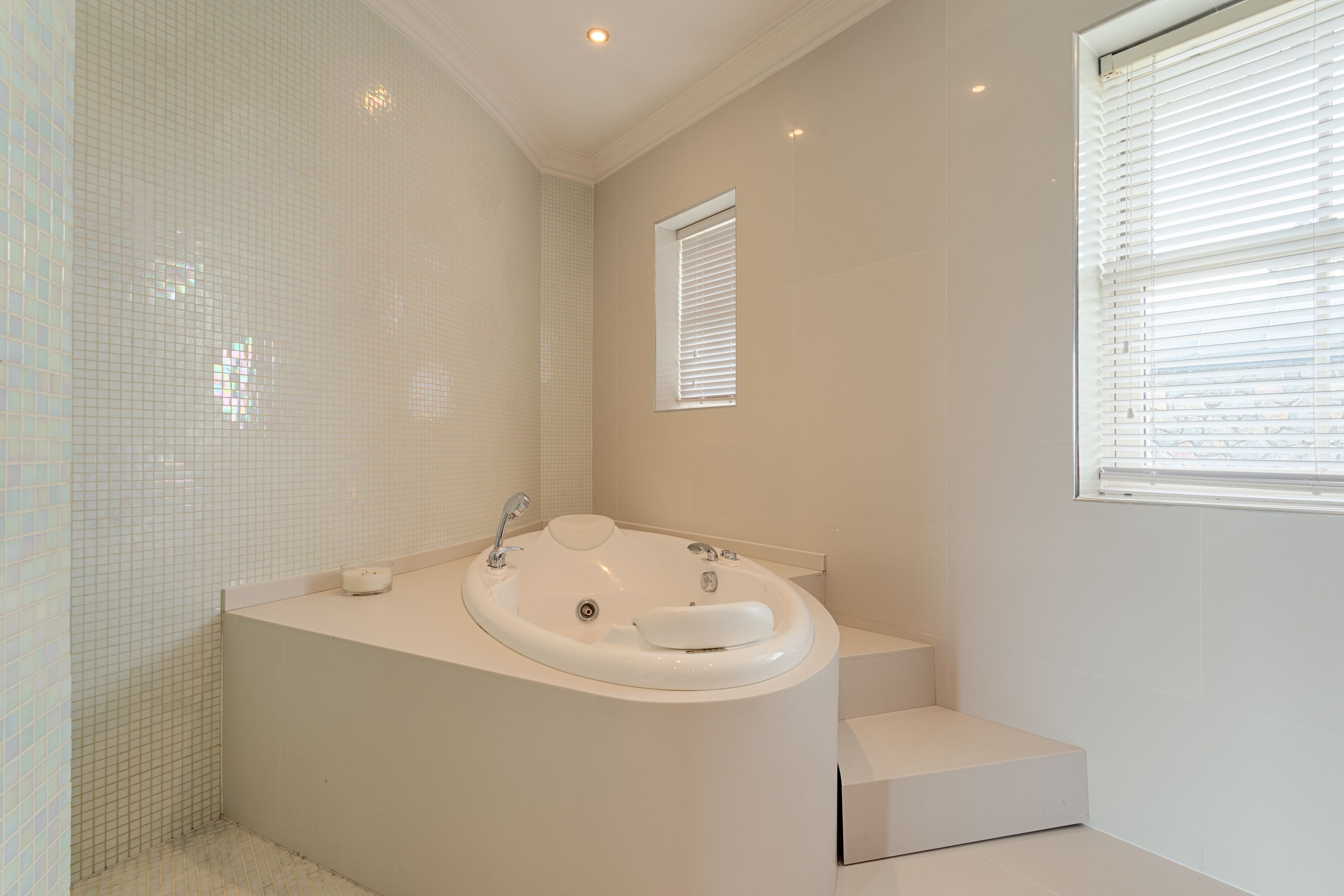 A modern bathroom with a freestanding bathtub, a small window, and a tiled floor.