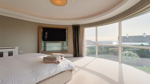 Un dormitorio con una cama grande, televisión y vistas a la ciudad.