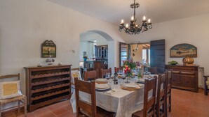A dining area with a table set for four, wooden chairs, a chandelier, and a wine rack. - Villa Ai Venti 8, Emma Villas (Massarosa)