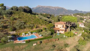 A villa with a swimming pool, surrounded by lush greenery and mountains in the background. - Villa Ai Venti 8, Emma Villas (Massarosa)