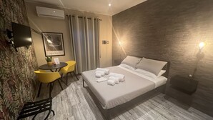 Une chambre d’hôtel équipée d’un lit, d’un bureau, d’une chaise, d’une télévision et d’une lampe fixée au mur.