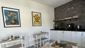 Une cuisine moderne avec des meubles blancs, un plan de travail en bois et un coin repas comprenant une table et des chaises en bois. Deux tableaux encadrés ornent le mur.