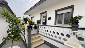 Un bâtiment blanc avec un toit gris, une balustrade blanche et un petit escalier menant à une porte marquée « ENTRÉE ».