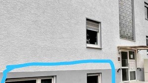 Un edificio con fachada texturizada, varias ventanas y una puerta con panel de vidrio.