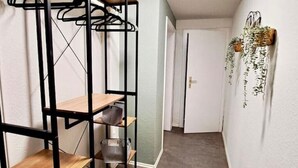 Pasillo con un armario metálico y estantes de madera, además de plantas colgantes.