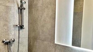A shower with a handheld showerhead and a fixed showerhead, mounted on a tiled wall. - Stylisches 1 Zimmer Apartment (Ludwigshafen am Rhein)