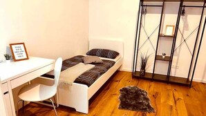 A small, modern bedroom with a bed, a desk, and a chair. There is a framed quote on the desk and a small plant on the desk. - Stylisches 1 Zimmer Apartment (Ludwigshafen am Rhein)