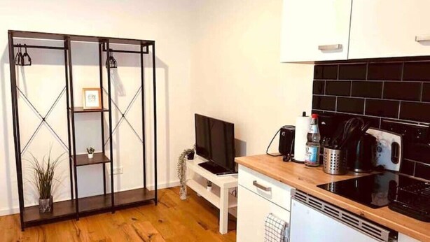 A compact kitchen with a black tiled backsplash, a white countertop, and a built-in dishwasher. - Stylisches 1 Zimmer Apartment (Ludwigshafen am Rhein)