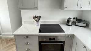 A kitchen with white cabinets, a black Bosch oven, a digital clock, and a toaster. - Regency Style Spacious Seaview Apartment. Sleeps up to 6 (Brighton and Hove)