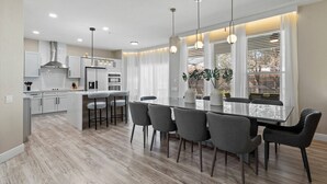 Une cuisine moderne dotée d’un îlot central, de tabourets de bar et de luminaires suspendus.