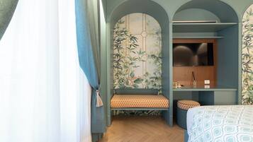 Ein modernes Hotelzimmer mit Holzboden, einem Bett mit gemusterten Betttextilien, einer Bank mit einem gemusterten Kissen, einem Fernseher und einer Wand mit Bambus-Wandgestaltung.