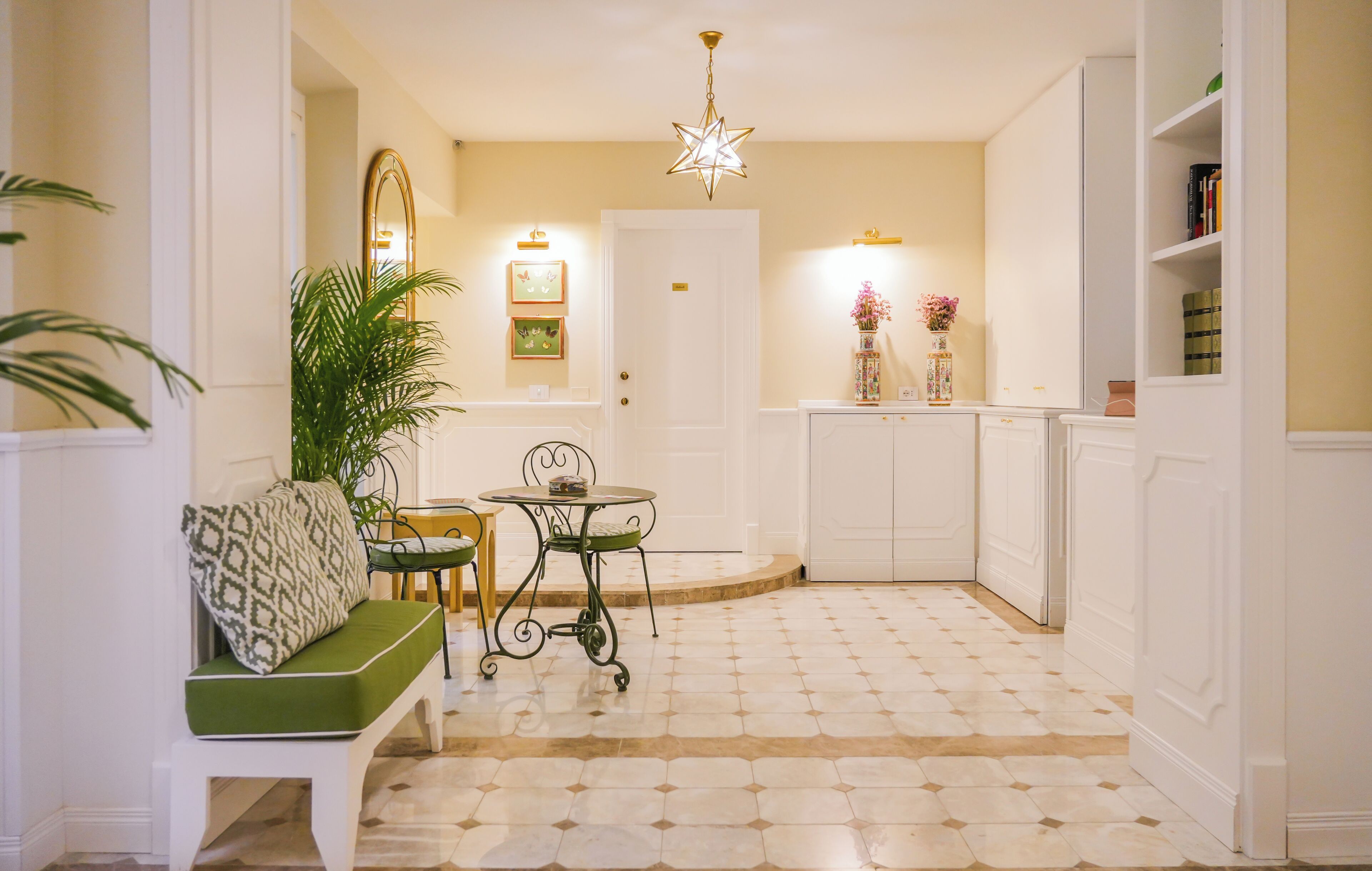 A hallway with a green bench, a small round table, and a decorative star-shaped light fixture.