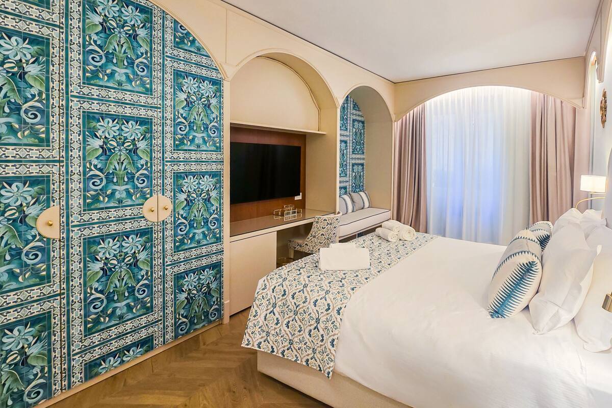 A hotel room with a bed, a TV, a desk, and a bathroom.