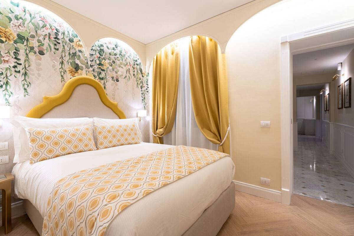 A bedroom with a bed, a headboard, and a floral wall decoration.