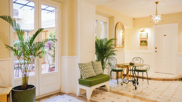 A well-lit hallway with a bench, a dining table with chairs, and potted plants. - La Dimora del Mercante (Florence)