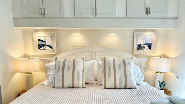 A neatly made bed with striped pillows, a headboard with a curved design, and two bedside lamps.