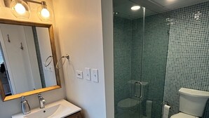 A modern bathroom with a glass-enclosed shower, a white sink, and a toilet.