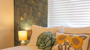 A bed with white bedding, a green decorative pillow, and a pillow with sunflower embroidery. - Restaurants, Cafes & Close to Downtown & Coronado (San Diego)