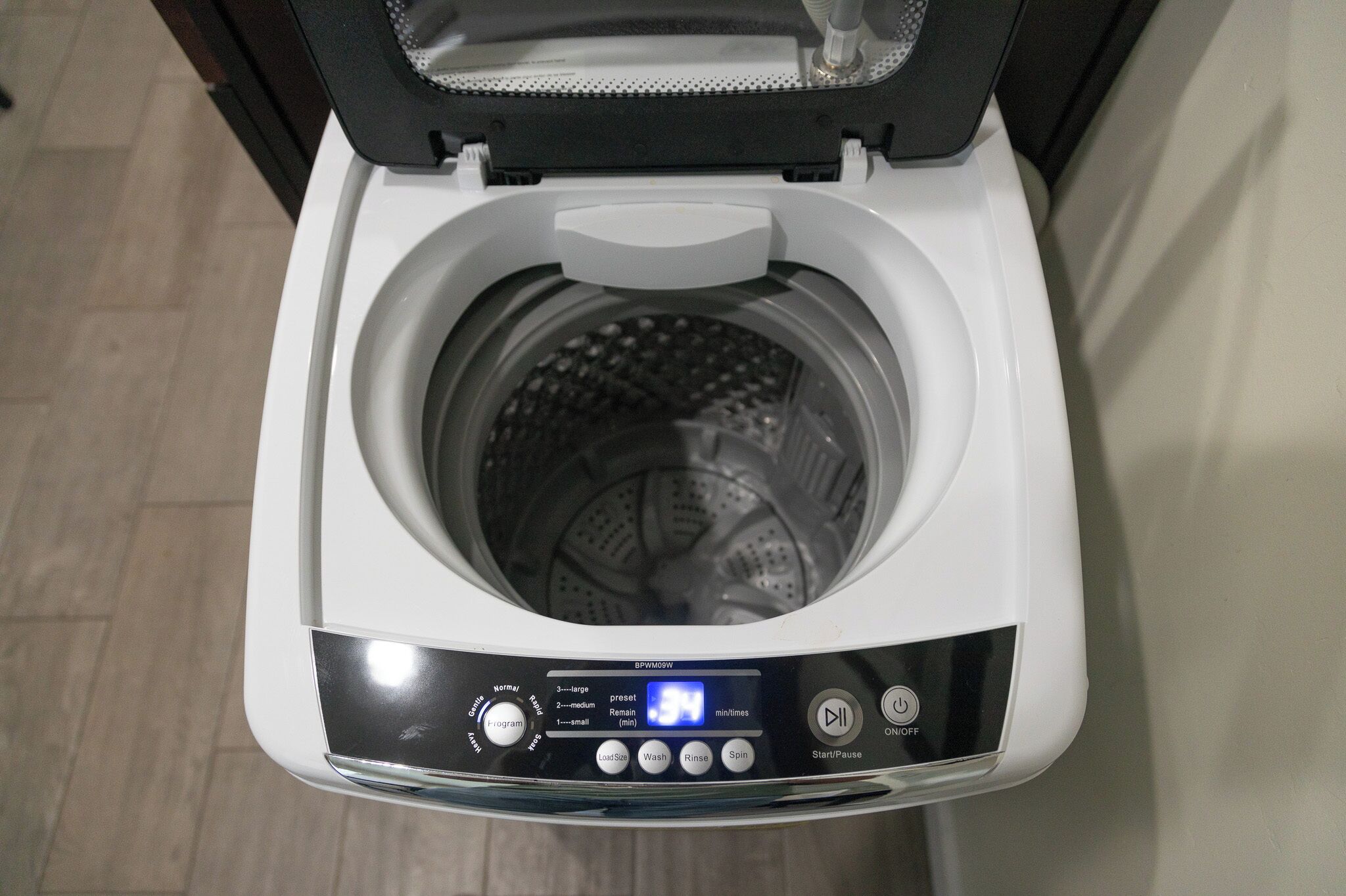 A front view of a modern, compact washing machine with a digital display, control panel, and a transparent door.