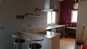 Een moderne keuken met een centraal eiland, barstoelen, een klok en een raam.