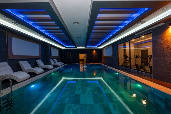 Una piscina techada, sillones reclinables de piscina