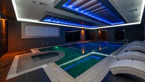 A modern indoor swimming pool with a clear water feature, a sunken seating area, and recessed lighting. - The Nirvanas Hotel (Istanbul)