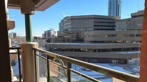 A balcony with a view of a parking garage and a tall building in the background. - Modern private One bedroom apartment Calgary Downtown #502 (Calgary)