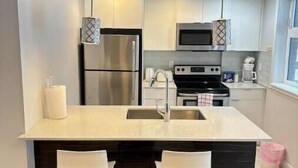 A modern kitchen with a central island, stainless steel appliances, and pendant lighting. - Modern private One bedroom apartment Calgary Downtown #502 (Calgary)