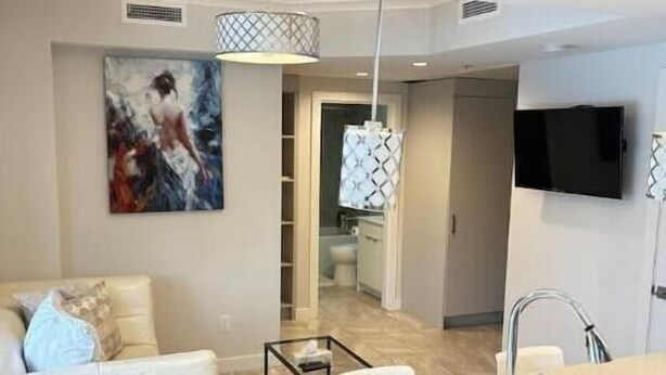 A modern kitchen with a central island, a built-in sink, and a dining area with a white table and chairs. - Modern private One bedroom apartment Calgary Downtown #502 (Calgary)