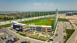 A modern building with a large parking lot and a sports field with colorful circular patterns.