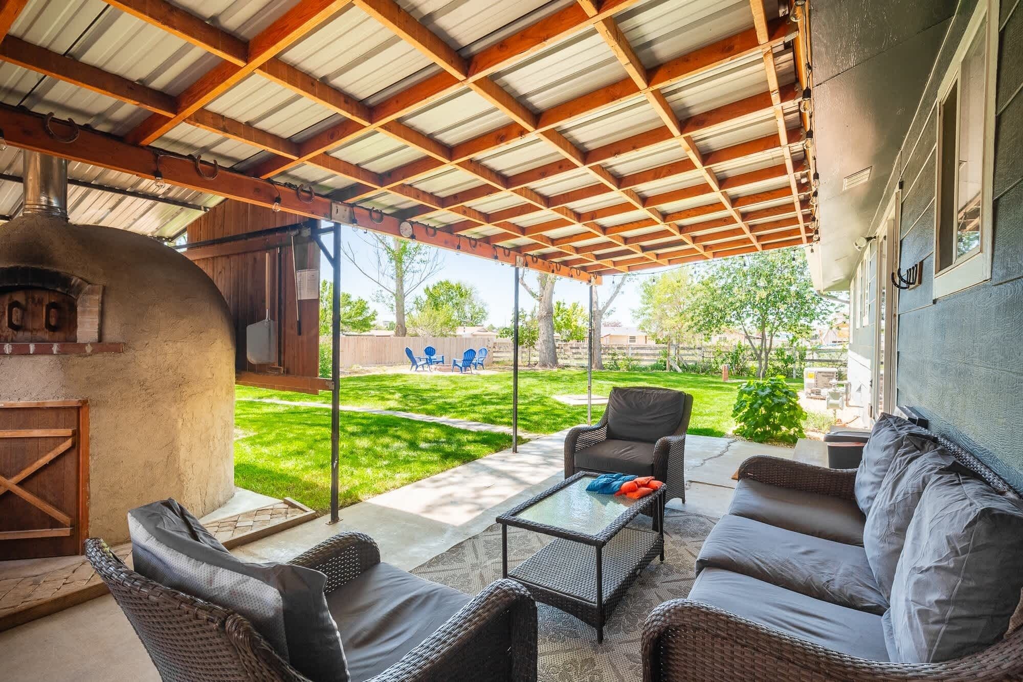 A covered patio area with wicker furniture, a glass-top table, and a wood-burning stove.