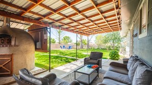 A covered patio area with wicker furniture, a glass-top table, and a wood-burning stove. - Centrally Located Family Home, Backyard w Firepit! (Meridian)