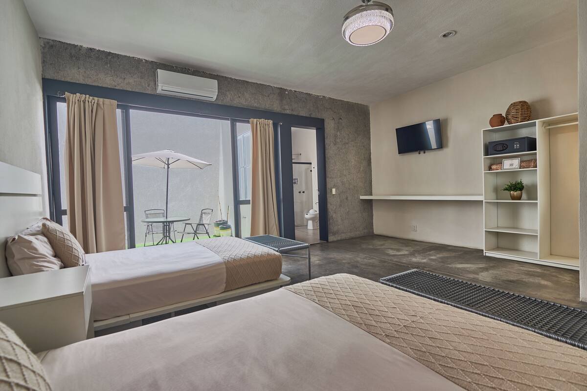 Habitación de hotel moderna con una cama grande, un escritorio, un televisor y un balcón con sombrilla.
