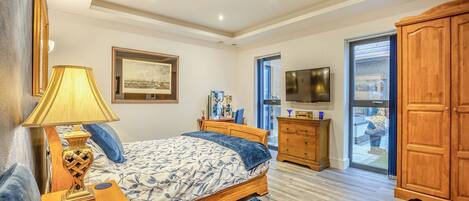 A bedroom with a bed, bedside table, lamp, dresser, TV, and a large wardrobe.