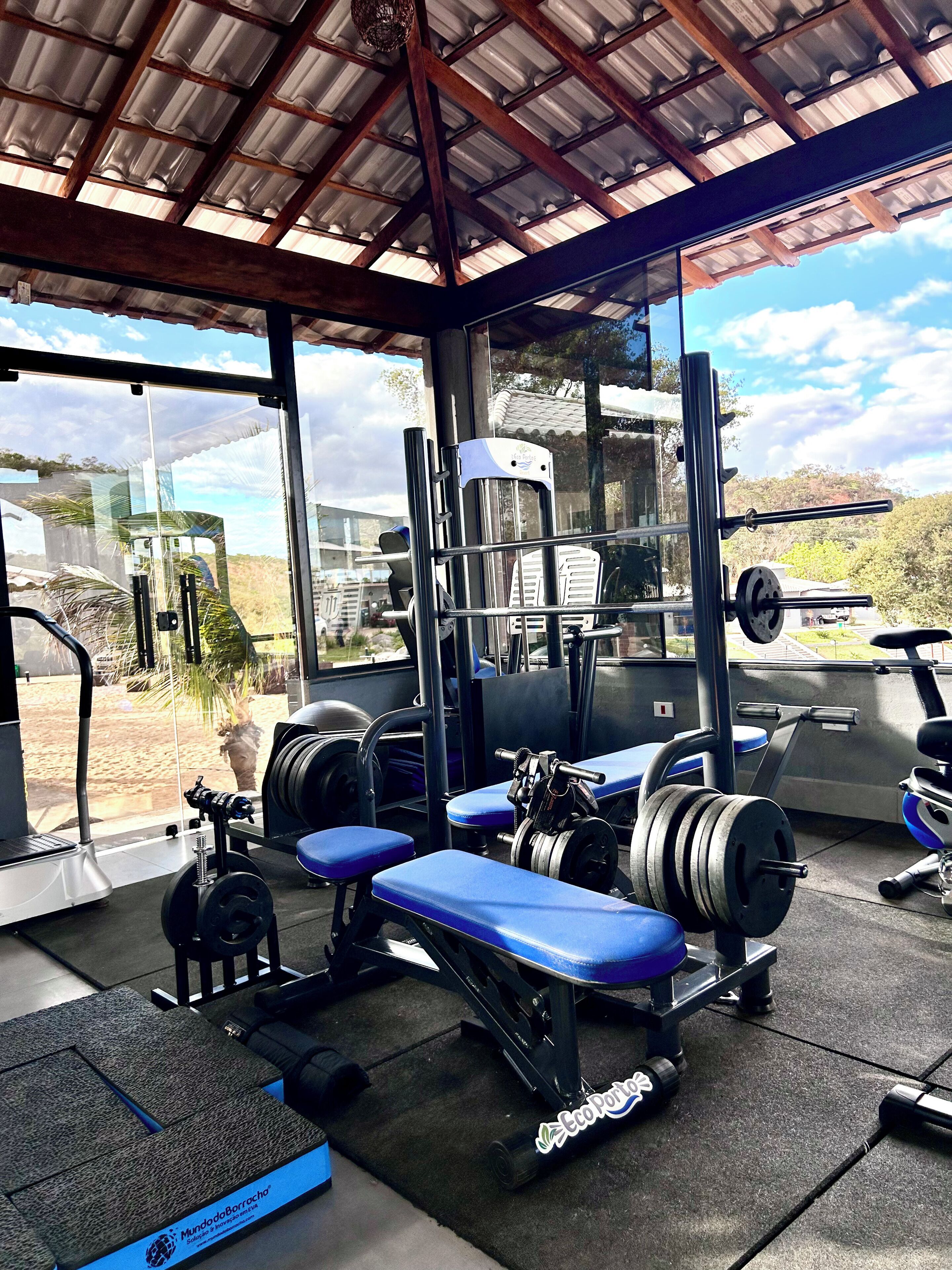 A gym with exercise equipment, benches, and a view of the outdoors.