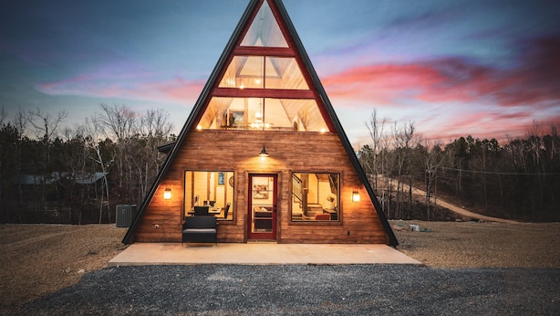 A triangular wooden cabin with a large glass window at the top, a door, and a small porch area. - Little Woods- Luxury A-frame cabin |Firepit|Hottub (Broken Bow)
