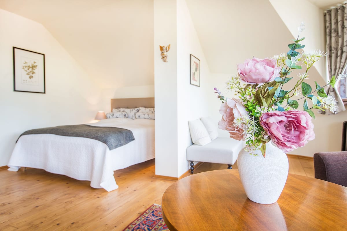 A bedroom with a bed, bedside table, and a vase with flowers.