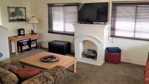 A living room with a fireplace, a television, a coffee table, and a couch. - Heart of the Falls! Cozy for 2, Spacious for 8, Close to everything! (Cuyahoga Falls)