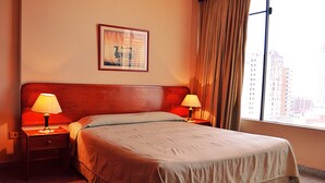 A hotel room with a large bed, two bedside tables with lamps, a framed picture on the wall, and a window with curtains. - hotel manduara (Asunción)