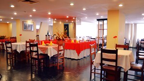 A restaurant with multiple tables and chairs, each covered with a tablecloth. - hotel manduara (Asunción)
