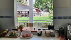 A kitchen with a view of a garden, a coffee machine, and various food items on the counter.