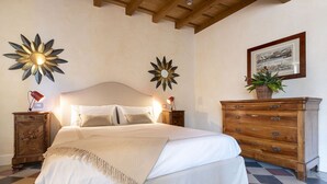 Een slaapkamer met een bed, twee wandlampen, een dressoir en een lijst met een foto aan de muur.