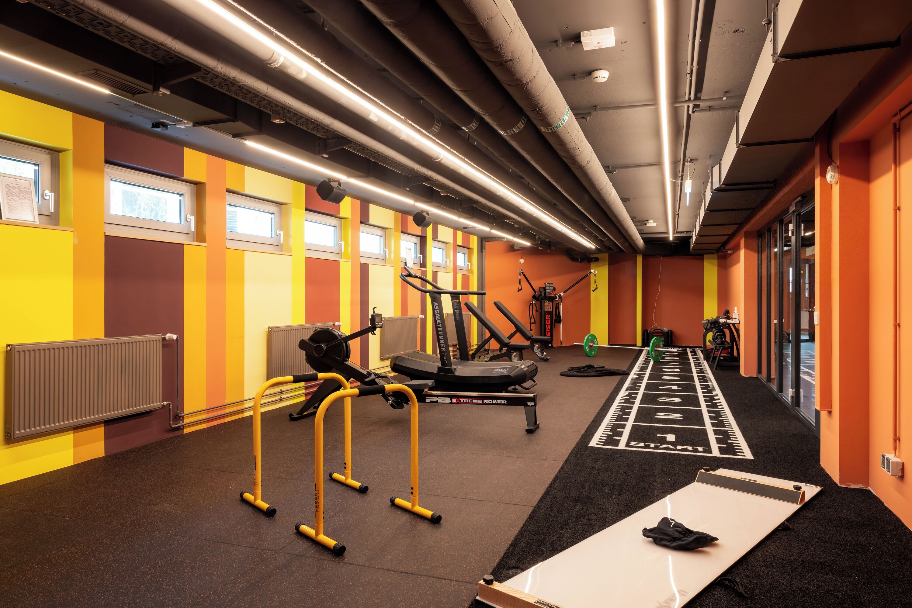 Un gimnàs amb equipament esportiu, una pista de running i un radiador.